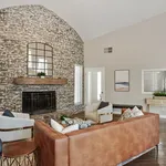 Chic living room with a rustic brick accent wall, stylish leather sofa, and plush armchairs surrounding a cozy fireplace.