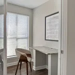 Chic home office nook with granite countertop and designer chair, illuminated by natural light through elegant blinds.