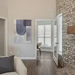 Inviting apartment living area with stylish decor, modern artwork, and a well-lit room with wooden flooring.