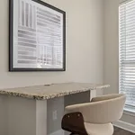 Bright home office corner featuring a sleek granite desk, modern art, and abundant natural light through large windows.