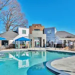 Inviting modern apartment complex with a sparkling outdoor pool and stylish cabanas under a clear blue sky.