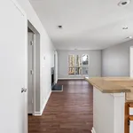 Inviting open-plan living area with hardwood floors, cozy fireplace, and abundant natural light through large windows.