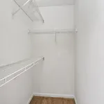 Spacious walk-in closet with sleek white wire shelving and plush carpet flooring, perfect for organized living.