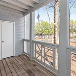 Charming apartment balcony with rustic wooden decking and serene forest views.