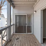 Charming sunlit balcony with sliding glass doors, featuring wood flooring and modern design.