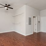 Modern apartment interior with sleek ceiling fan and rich wood flooring, featuring minimalist wall shelves and neutral walls for a spacious and airy feel.