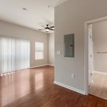 Bright and airy living space with sleek wooden floors, contemporary ceiling fan, and ample natural light through vertical blinds.