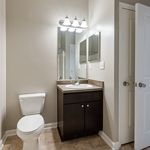 Bright and modern bathroom with sleek fixtures, featuring a large mirror, elegant vanity, and pristine white toilet.