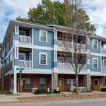 Charming modern apartment complex with blue siding, spacious balconies, and cozy brick accents in a serene neighborhood setting.