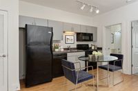 Contemporary kitchen with sleek black appliances, stylish gray cabinets, and a chic dining setup perfect for modern living.
