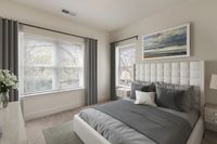 Elegant bedroom with plush bedding, large windows, and calming wall art, creating a serene and inviting atmosphere.