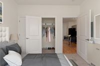 Inviting bedroom with plush bedding, ample closet space, and a view into the modern dining area with elegant decor and open layout.