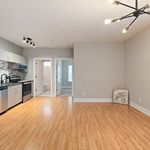 Modern open-plan kitchen and living area with sleek design, featuring light wood floors, contemporary lighting, and stylish cabinetry.