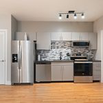 Modern kitchen with sleek stainless steel appliances, elegant tile backsplash, and stylish cabinetry on hardwood flooring.