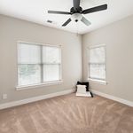 Bright, airy room with plush carpeting, large windows, and ceiling fan, perfect for comfortable living.