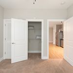 Chic interior view with a cozy carpeted room leading to a modern kitchen featuring a sleek stainless steel refrigerator.