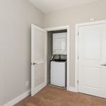 Bright modern space featuring a convenient in-unit laundry closet with a sleek stacked washer and dryer.