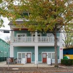 Charming duplex with lovely green facade and inviting balconies, surrounded by vibrant autumn foliage.