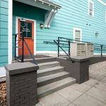 Charming apartment building entrance with vibrant teal siding and a welcoming red door at The Davy Apartments.