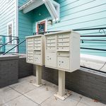 Charming residential entrance featuring pastel turquoise siding and modern dual mailbox units, enhancing curb appeal.