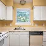 Cozy kitchen with warm beige walls, white cabinetry, and a double sink beneath a bright window.