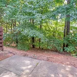 Serene apartment patio retreat with lush green trees providing a natural, calming backdrop.