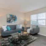 Bright and inviting living room with modern gray sofas, abstract wall art, and a stylish glass coffee table, perfect for relaxation.