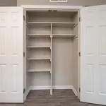 Spacious built-in closet with elegant white double doors and ample shelving, perfect for organized storage.