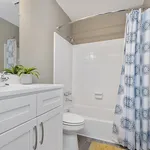 Bright and modern bathroom with elegant white vanity, chic shower curtain, and a touch of greenery for a refreshing ambiance.