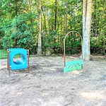 Charming pet-friendly play area in a serene wooded setting, complete with engaging agility obstacles perfect for your furry friend's enjoyment.