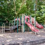 Charming playground featuring vibrant slides and tunnels surrounded by lush greenery. Ideal for family-friendly apartment living.