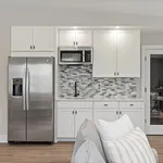 Modern kitchen with sleek stainless steel refrigerator, elegant white cabinets, and stylish mosaic backsplash.