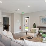 Modern living room with stylish decor, featuring comfortable seating, artistic wall accents, and natural light from a glass door, creating an inviting atmosphere.