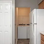 Contemporary laundry nook with washer and dryer, adjacent to a modern kitchen with sleek refrigerator.