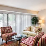 Charming living room with stylish striped chairs, cozy sofa, large window with blinds, and elegant decor.