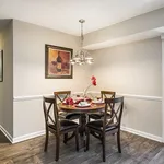 Elegant dining area featuring a round wooden table set for four with stylish decor and ambient lighting.