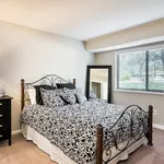 Inviting bedroom with elegant iron bed, stylish bedding, and large window offering natural light and garden views.