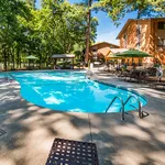 Inviting outdoor pool area with modern loungers and vibrant green surroundings, perfect for relaxation and leisure.