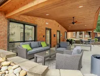 Charming outdoor patio with cozy wicker furniture and vibrant cushions under a warm wooden pergola, perfect for relaxation and social gatherings.