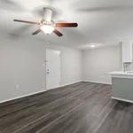 Modern apartment with elegant ceiling fan and sleek wooden flooring, featuring an inviting open-plan layout with a bright kitchen area.