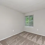 Bright and inviting room with plush carpet and a large window overlooking greenery, creating a cozy and serene atmosphere.