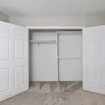 Spacious and modern walk-in closet with white double doors and sleek interior shelving, perfect for organized living.
