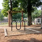 Charming outdoor space with bike rack, wooden pergola, and lush greenery, perfect for relaxation and nature lovers.