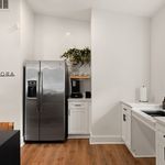 Sleek modern kitchen with stainless steel refrigerator, elegant cabinetry, and warm wood flooring.
