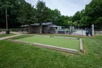Charming outdoor recreation area featuring a manicured bocce ball court and a nearby swimming pool in a lush green setting.
