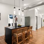 Contemporary dining area with elegant pendant lighting, sleek black table, and stylish woven chairs on polished wood flooring.