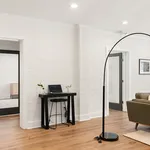 Chic apartment interior featuring a modern white brick wall, sleek black furnishings, and warm wood flooring.