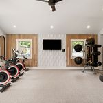 Modern home gym with stylish wall decor, equipped with exercise bikes and fitness equipment, offering a vibrant workout space.