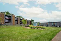 Modern apartment complex with lush green lawns and a stylish architectural design under a clear blue sky.