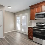 Bright kitchen with sleek stainless steel appliances, rich wooden cabinetry, and elegant French doors opening to a sunlit space.